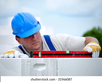 Mason checking horizontal level of house wall  layer being made from aerated autoclaved concrete blocks - Shutterstock ID 31966087