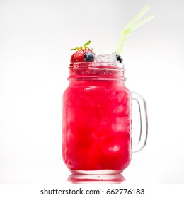 Mason Jar Of Bright Pink Lemonade With Ice, Strawberries, Blueberries And Yellow Drinking Straws On Light Background