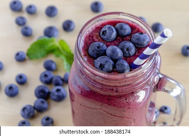 Mason Jar Filled With Blueberry And Blackberry Fresh Fruit Smoothie Sitting On Counter With Bowl Of Blueberries