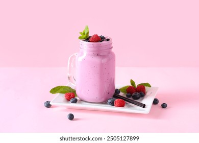 Mason jar of fresh smoothie with blueberries and raspberries on pink background - Powered by Shutterstock