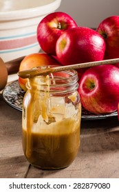 Mason Jar With Spoon And Caramel Sauce And Red Apples