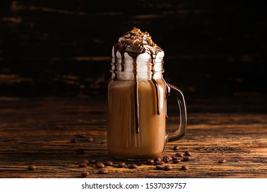 Mason Jar Of Tasty Frappe Coffee On Wooden Table