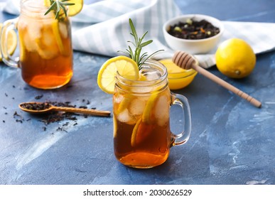Mason jars of cold black tea with lemon on color background