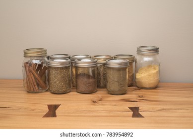 Mason Jars Filled With Spices Sitting On A Raw Edge Oak Tabletop.