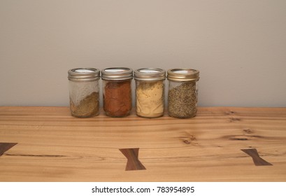 Mason Jars Filled With Spices Sitting On A Raw Edge Oak Tabletop.