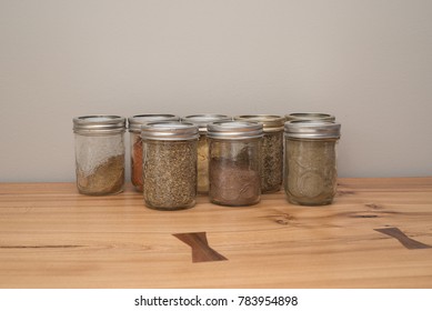 Mason Jars Filled With Spices Sitting On A Raw Edge Oak Tabletop.