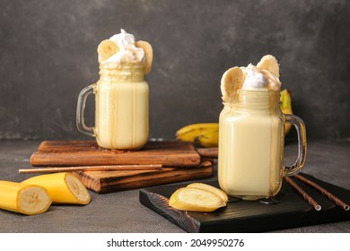 Mason jars of tasty banana milkshake on dark background