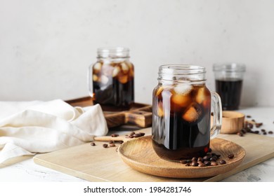 Mason jars of tasty cold brew and coffee beans on white background - Shutterstock ID 1984281746