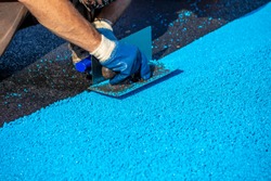 Mason Leveling Artificial Rubber Coating For Playgrounds And  Sports, Applied On The Surface By A Steel Trowels. PDM Rubber Granules. Selective Focus.