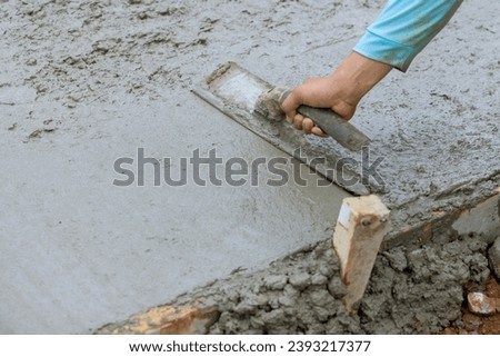 Mason leveling fresh concrete pavement with wet cement using special working tools