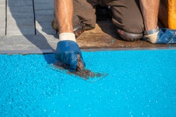 Mason Leveling Rubber Coating For Playgrounds With Trowel, Mason Hand Spreading Soft Rubber Crumbs. Outdoor Soft Coating And Floor Covering For Sports. Rubber Mulch For Safety. Selective Focus.