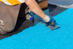 Mason Leveling Rubber Mulch Coating For Playgrounds And  Sports, Applied On The Surface By A Steel Trowels. PDM Rubber Granules. Selective Focus.