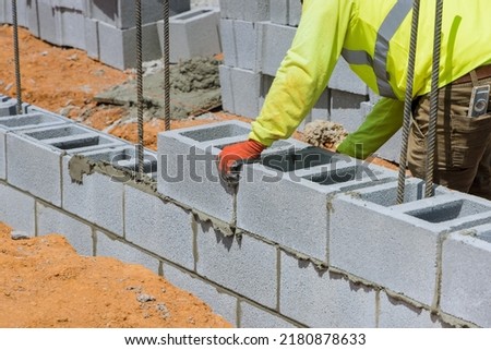 A mason is in the process of mounting a wall of aerated concrete blocks using masonry techniques on construction site