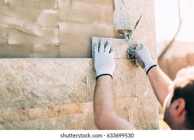 Mason Worker Installing Stone Tiles On Wall On Construction Site