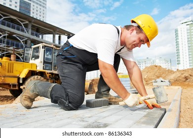 mason worker making sidewalk pavement with stone blocks