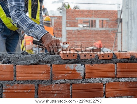 Masonry work, close up of worker laying brick of an office building at a construction site. Architectural work, under construction.