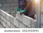 masonry worker make concrete wall by cement block and plaster at construction site                  