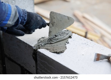 masonry worker make concrete wall by cement block and plaster at construction site - Shutterstock ID 2157612473