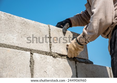 masonry worker make concrete wall by cement block and plaster at construction site 