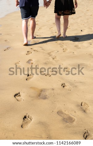 Maspalomas, Canarias islands/ Spain-July 22, 2018: Couple of man and woman walking on Canarias sand from Sahara desert, view of wet foot traces. Blue Atlantic ocean and beach on Gran Canaria. 
