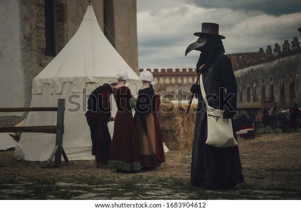 A masquerade historical scene reconstruction. Plague doctor in medieval old town. Castle and epidemic