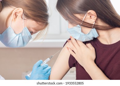 Mass global vaccination of teenagers against covid-19 coronavirus, a doctor injects a vaccine to a patient girl