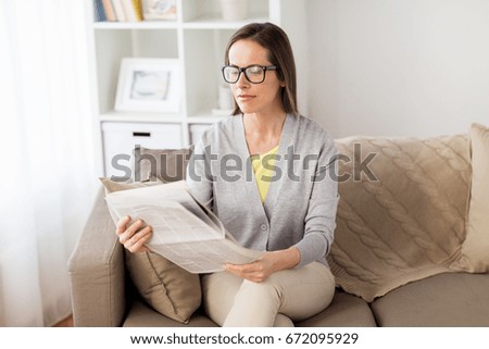 mass media and people concept - happy woman reading newspaper at home