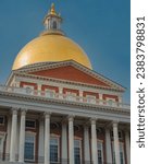The Massachusetts State House, a historic building in Boston, stands proud with its golden dome and red brick facade against a clear blue sky.