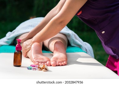 Massage of legs, female feet with oil, stones outdoors. Close up photo of woman foot and therapist's hands of masseur, massagist. Professional physiotherapist. Unrecognisable person is lying, relaxing - Powered by Shutterstock