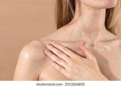 Massage oil application under collarbone with hand you woman against beige background - Powered by Shutterstock