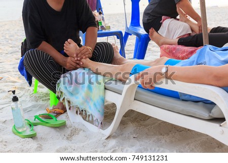 Massage oil foot relaxation on the beach background.