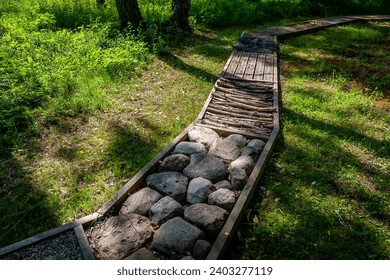 Massage path with different textures, flatfoot prevention, natural tactile sensory path, stones, logs, fir cones. Health path in nature.