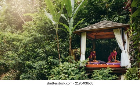 Massage Pavilion Surrounded By Trees With Couple Receiving Body Massage. Outdoor Spa Center At Holiday Resort.