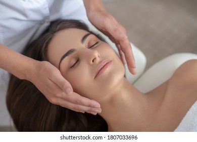 Massage. Professional massage therapist doing face massage to a customer