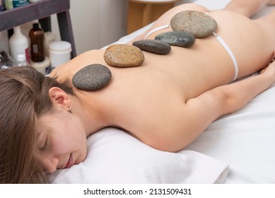 Massage Session For A Young Woman, Relaxing And Harmonics In A Beauty Center With Balls, Algae, Aromatic Oils And Reiki Stones, Performed By A Beautician.