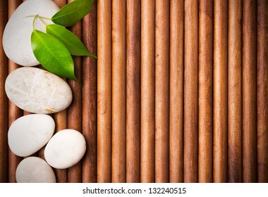 Massage stones with green leaves, wood background.