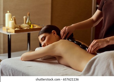 Massage stones on  back of a woman at the spa salon
