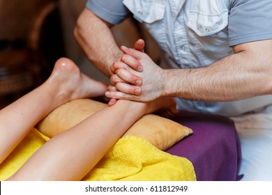 massage therapist does a foot massage to a young attractive girl at the spa salon