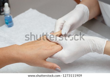 Massage therapist in latex gloves massaging hands of a woman in a beauty salon, closeup