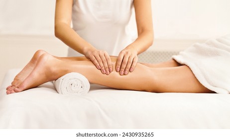 Massage therapist massaging woman calves in spa center, side view - Powered by Shutterstock