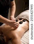 A massage therapist places hot stones on a client