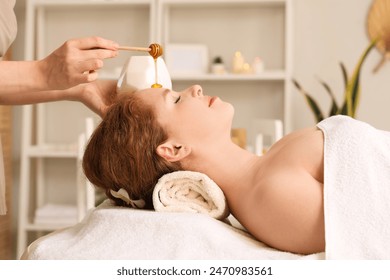 Massage therapist pouring honey on woman's face in spa salon, closeup - Powered by Shutterstock