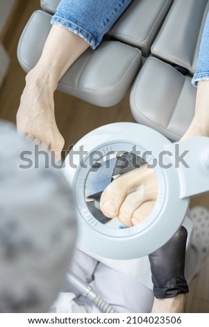 massage and treatment of legs and feet at a podiatrist doctor with a magnifying glass, scraper, scissors, sanding, file, medicine, fingers, manicure, pedicure