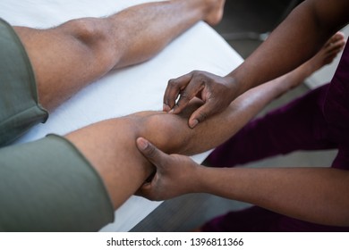 Massaging knee. Close up of dark-skinned massage therapist massaging knee for sportsman - Powered by Shutterstock