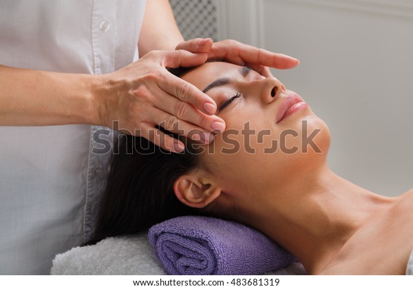 Massagist with woman patient in aroma spa\
wellness center. Professional face lifting massage to beautiful\
girl in cosmetology cabinet or beauty\
parlor.