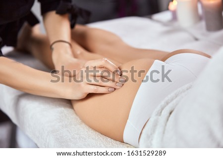 masseur arm massaging woman ass in white panties at beauty salon, beautician doing anticilulite massage for female body