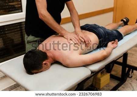 masseur doctor makes body massage to a middle-aged man at home. prophylactic massage. examination of the back and body. massage therapist call