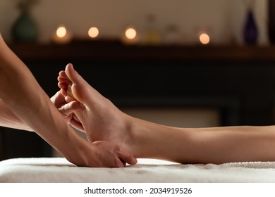 Masseur doing a foot massage with candles on background - Powered by Shutterstock