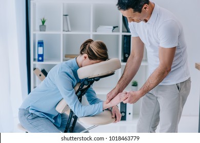 masseur doing hands massage for businesswoman at office