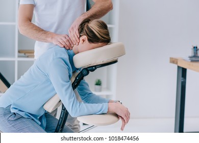 masseur doing seated neck massage for businesswoman - Powered by Shutterstock